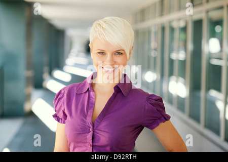 Porträt von zuversichtlich attraktive Geschäftsfrau lächelnd und Blick in die Kamera aus Bürogebäude Stockfoto