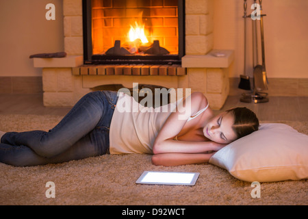 Schöne Frau Entspannung durch Feuer neben digital-Tablette Stockfoto