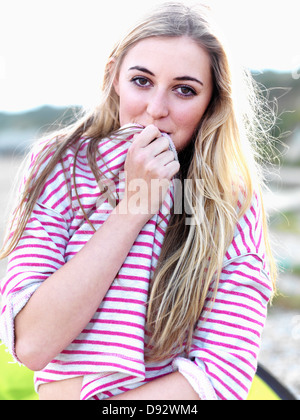 Eine junge Frau ihren Mund mit ihrem Shirt und spielerisch lächelnd Stockfoto