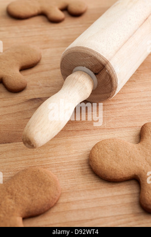 Erhebungen von Lebkuchenmänner auf einem Holztisch mit einem Nudelholz, Nahaufnahme Stockfoto