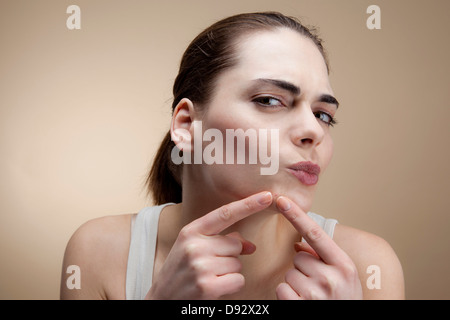 Eine junge Frau konzentrieren, als sie einen Pickel drückt Stockfoto