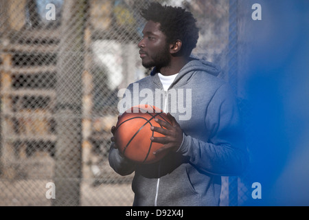 Ein hip junger Mann wegsehen nachdenklich einen Basketball mit gedrückter Stockfoto