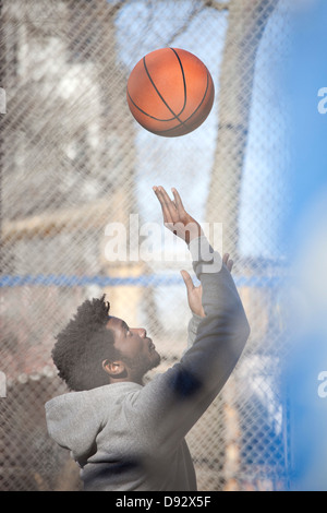 Ein hip junger Mann spielen Basketball auf einem öffentlichen Freiplatz Stockfoto