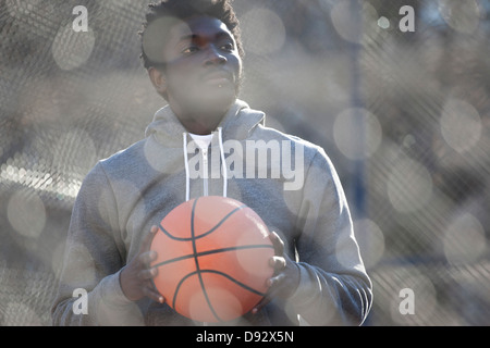 Ein hip junger Mann wegsehen nachdenklich einen Basketball mit gedrückter Stockfoto