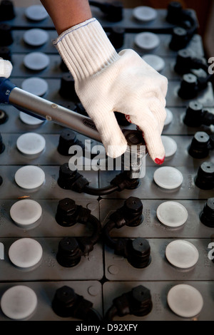 Ein Arbeitnehmer anziehen von Schrauben auf einem solar Power Akku Stockfoto