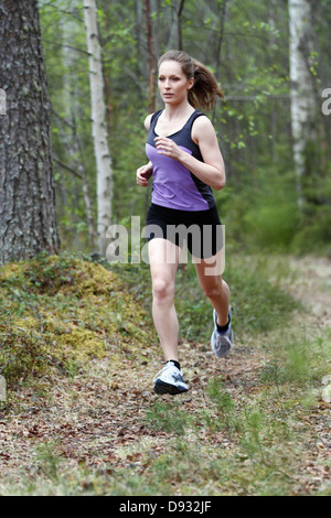 Junge Frau läuft durch den Wald Stockfoto