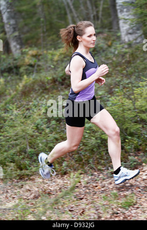 Junge Frau läuft durch den Wald Stockfoto