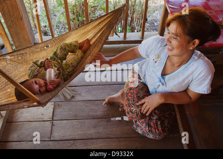 Eine Mutter rockt ihr Baby in einem SHAN-Dorf in der Nähe von KENGTUNG auch bekannt als KYAINGTONG - MYANMAR Stockfoto