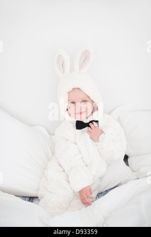 Mädchen mit Hase Kostüm sitzt auf Bett Stockfoto