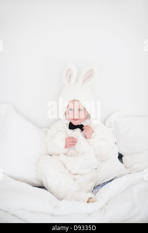 Mädchen mit Hase Kostüm sitzt auf Bett Stockfoto