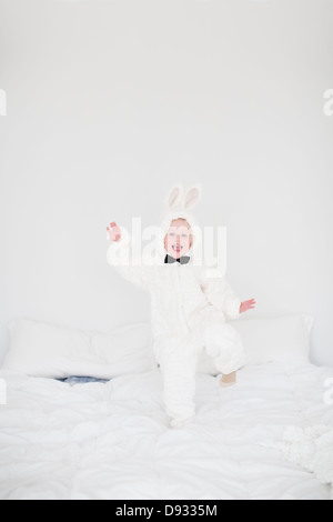 Mädchen mit Hase Kostüm tanzen auf Bett Stockfoto