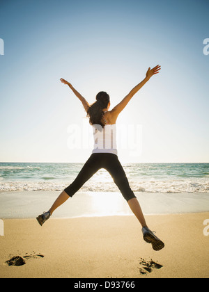 Gemischte Rassen Frau springen vor Freude am Strand Stockfoto