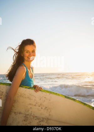 Gemischte Rassen Frau mit Surfbrett am Strand Stockfoto