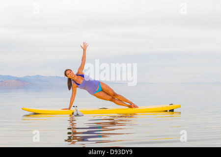 Philippinische Frau praktizieren Yoga auf Paddel board Stockfoto