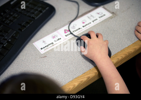 Ein Kind an der Hand hält eine Computer-Maus auf dem Schreibtisch Stockfoto