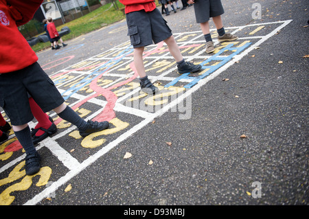 Kinder spielen auf einem nummerierten Planquadrat auf dem Spielplatz der Grundschule Stockfoto