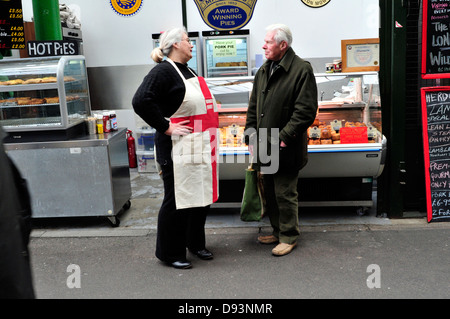 Ein Stall-Inhaber trägt eine englische Flagge-Schürze, Gespräch mit einem Kunden im Borough Market, London Stockfoto