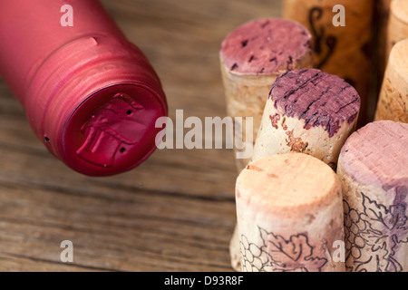 Einige Weinkorken werden zusammen mit einer Flasche Wein auf einem hölzernen Hintergrund gesperrt. Stockfoto