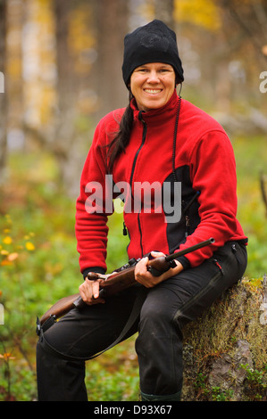 Mitte Erwachsene Frau Holding Gewehr im Wald Porträt Stockfoto