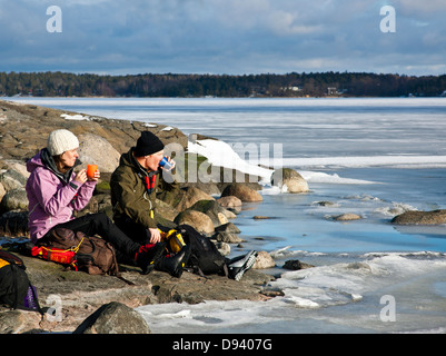 Junges Paar Kaffeetrinken auf Felsen auf dem Seeweg Stockfoto