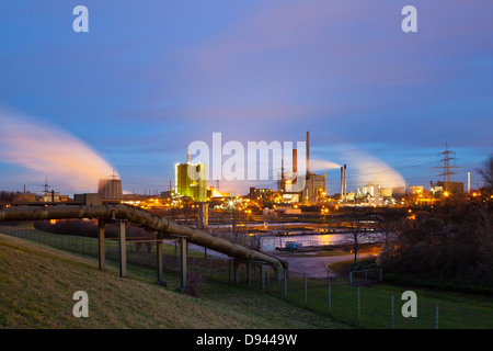 Industrielandschaft mit blauen Nachthimmel, einer Pipeline im Vordergrund. Stockfoto