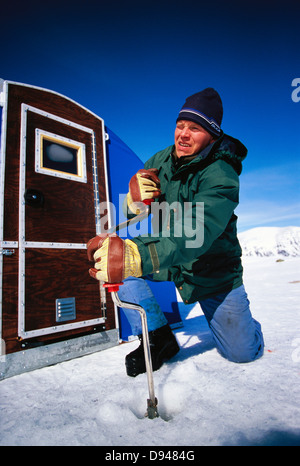 Ein Mann trug ein Loch in das Eis, Lappland, Schweden. Stockfoto