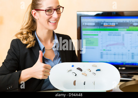 Junge Frau oder Anhörung Accoustician hält eine Auswahl von Hörgeräten Stockfoto