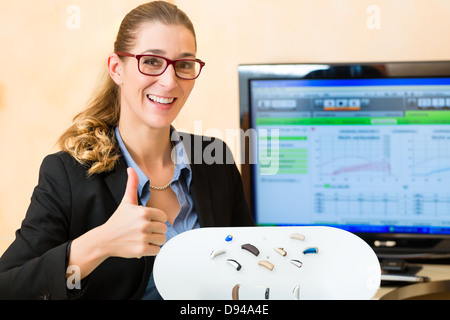 Junge Frau oder Anhörung Accoustician hält eine Auswahl von Hörgeräten Stockfoto