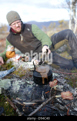 Mann kochendes Wasser im Wasserkocher auf Feuer Stockfoto