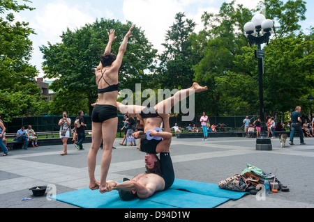 New York, USA 11. Juni 2013 - Acro Yoga Interpreten im Washington Square Park führen ausgleichende Tricks während des Spielens Ukelele © Stacy Walsh Rosenstock/Alamy Stockfoto