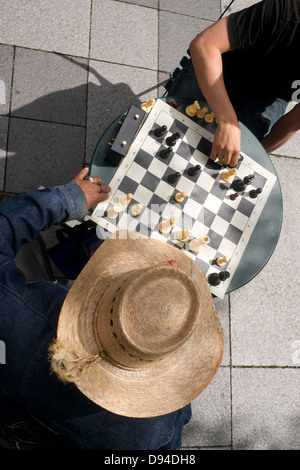 Ein Mann geht seinen Turm in einer Partie Schach auf der Straße Stockfoto