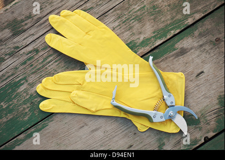 Gelbe Gummihandschuhe und Garten Astschere auf hölzernen Hintergrund. Closeup. Stockfoto