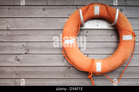 Roten Rettungsring mit Seil auf verwitterter Holzwand im Hafen Stockfoto