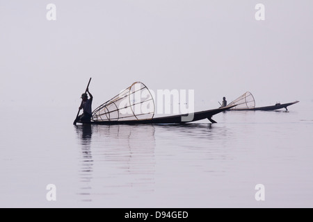 Traditionelle 'Bein Ruderer' Fischer am Inle-See tragen die traditionelle "Longyi" mit einem Bambuskorb Angeln in Birma Stockfoto