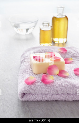 Rosenblüten und Badezusätze wie Handtuch, Seife und Flaschen von ätherischen Ölen für die Aromatherapie und wellness Stockfoto