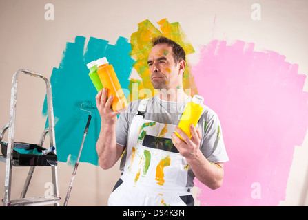 Reife Mann Renovierung seiner Wohnung und Entscheidung zwischen Lackfarben Stockfoto