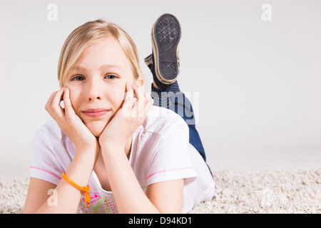 Porträt eines Mädchens stützte sich auf Händen und liegend auf Bauch im Studio Stockfoto