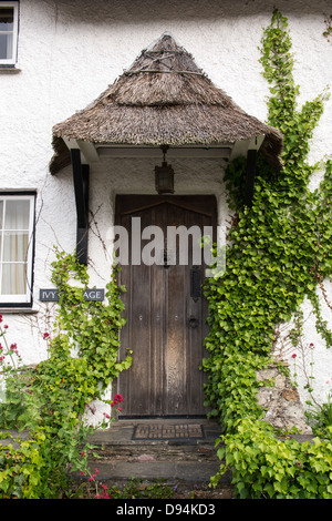 Ivy eine strohgedeckte Cob Hütte Tür umgibt. Devon, England Stockfoto
