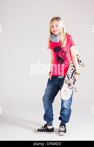 Full Length Portrait eines Mädchens mit Skateboard im Studio Stockfoto