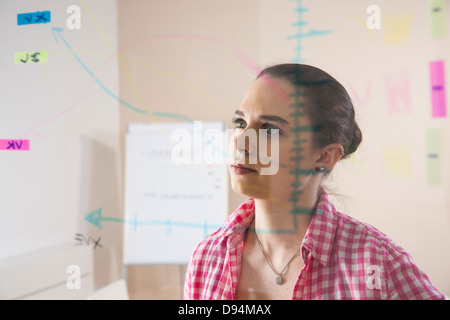 Junge Geschäftsfrau arbeiten im Büro Blick auf Pläne, die auf eine Glasplatte angezeigt Stockfoto