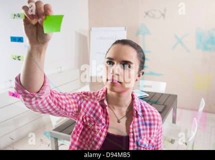 Junge Geschäftsfrau arbeiten im Büro, verbinden mit Klebstoffe Notizen, Pläne, die auf eine Glasplatte angezeigt Stockfoto
