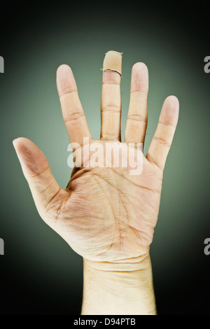 Nahaufnahme des männlichen linken mit Bandage am Mittelfinger, Studioaufnahme Stockfoto