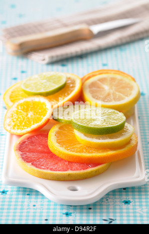 Nahaufnahme der Scheiben von Zitrusfrüchten auf Schneidebrett auf blauem Hintergrund Stockfoto