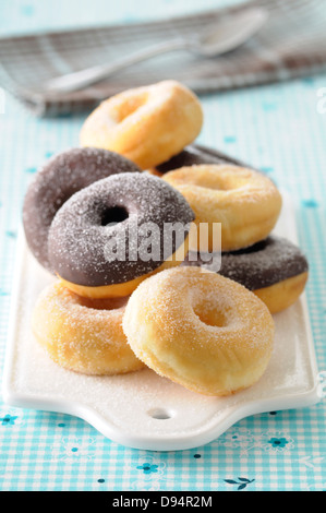 Nahaufnahme von Zucker überzogen und Schokolade getaucht Donuts auf Schneidebrett auf blauem Hintergrund Stockfoto