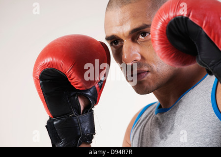 Mann trägt Boxhandschuhe im Studio mit weißem Hintergrund Stockfoto