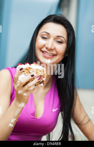 Schönes Mädchen essen einen Stück Kuchen mit Sahne bestrichen Stockfoto