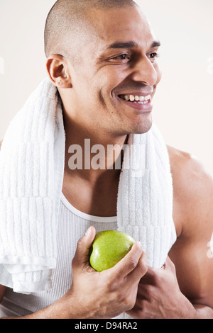 Mann trägt Arbeit Kleidung und Essen und Apple im Studio mit weißem Hintergrund Stockfoto