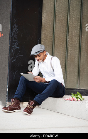 Porträt des Mannes sitzt auf Schritt mit Blumen, mit einem Tablet, Mannheim, Baden-Württemberg, Deutschland Stockfoto