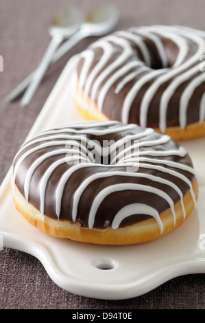 Nahaufnahme von Schokolade getaucht Donut mit Vanille Streifen auf Schneidebrett, Studioaufnahme Stockfoto