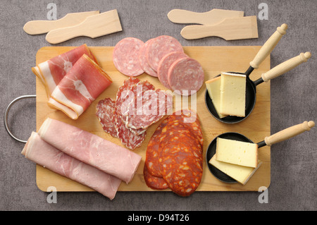 Draufsicht von Wurst und Käse für Raclette auf Schneidebrett auf grauem Hintergrund, Studioaufnahme Stockfoto